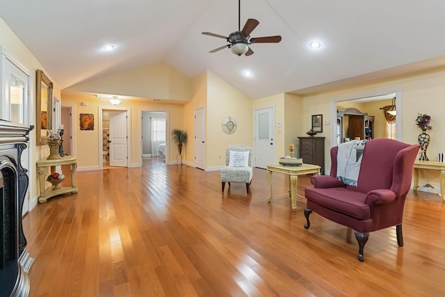 sitting room featuring lofted ceiling, a fireplace, a ceiling fan, baseboards, and light wood-type flooring