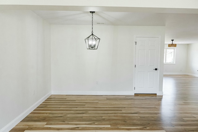 unfurnished dining area featuring visible vents, baseboards, and wood finished floors