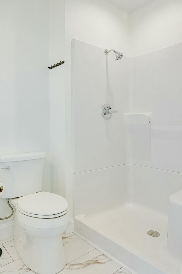 full bathroom with marble finish floor, a stall shower, toilet, and baseboards