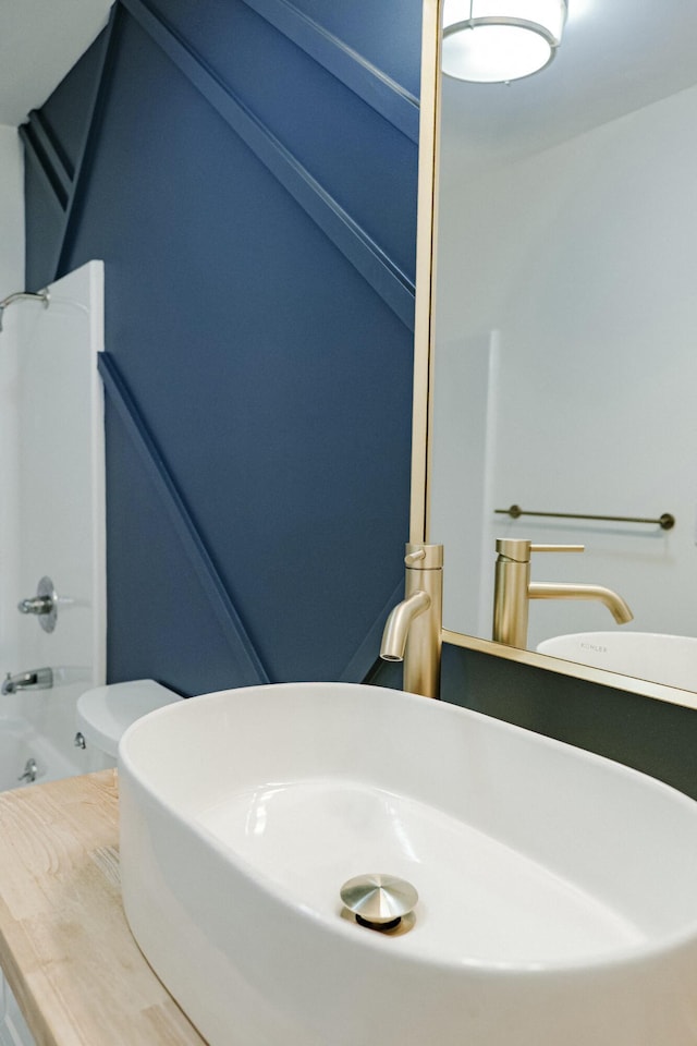 bathroom with toilet, shower / tub combination, and a sink