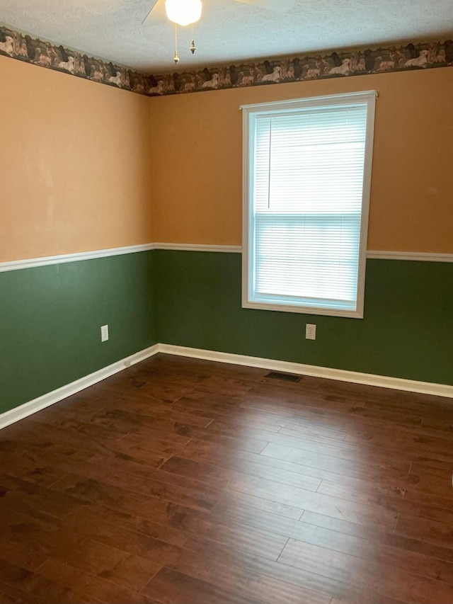 unfurnished room featuring dark wood-style floors, baseboards, visible vents, and a textured ceiling