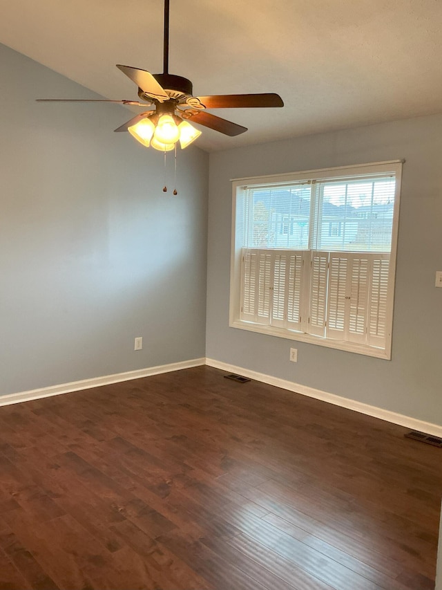 spare room featuring visible vents, dark wood finished floors, and baseboards