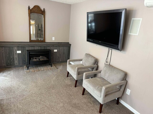 sitting room featuring carpet floors, a wall mounted air conditioner, a fireplace, and baseboards