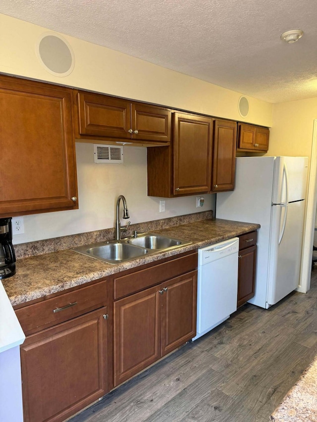 kitchen featuring white appliances, a textured ceiling, dark wood-style flooring, and a sink