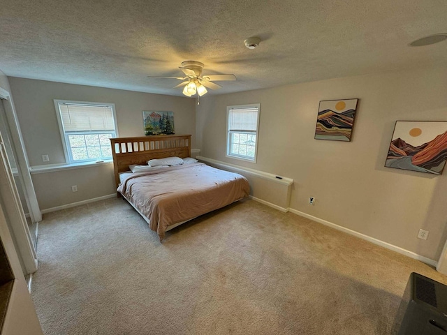 carpeted bedroom featuring a textured ceiling, a ceiling fan, and baseboards