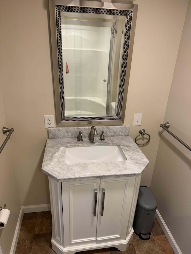 bathroom featuring toilet, an enclosed shower, vanity, and baseboards