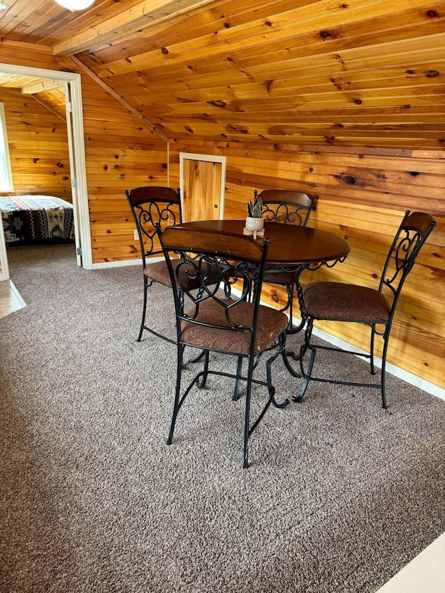 dining area with carpet floors, wooden ceiling, vaulted ceiling, and wooden walls