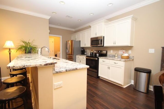 kitchen with white cabinets, appliances with stainless steel finishes, a peninsula, a kitchen bar, and a sink