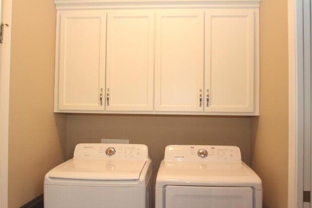 laundry area with separate washer and dryer and cabinet space