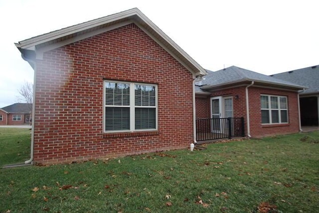 view of property exterior with brick siding and a lawn