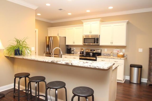 kitchen with stainless steel appliances, dark wood-type flooring, a breakfast bar, white cabinets, and crown molding