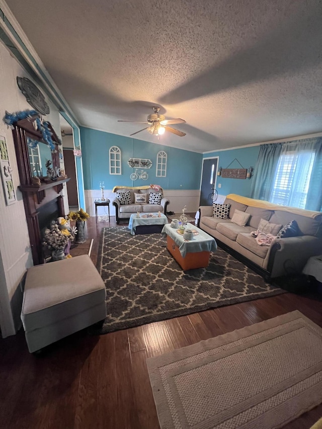 living area with ceiling fan, hardwood / wood-style floors, a textured ceiling, and a fireplace