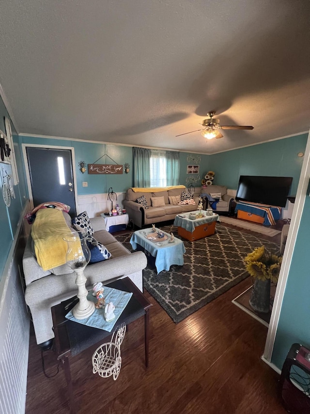 living room with ceiling fan, a textured ceiling, ornamental molding, and wood finished floors