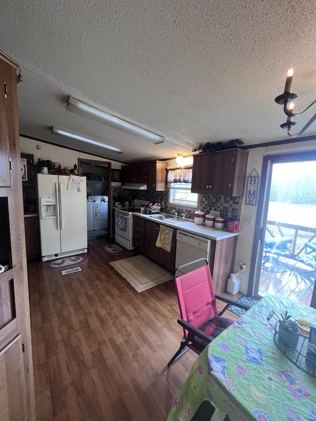 kitchen featuring white appliances, dark wood finished floors, washing machine and clothes dryer, light countertops, and under cabinet range hood