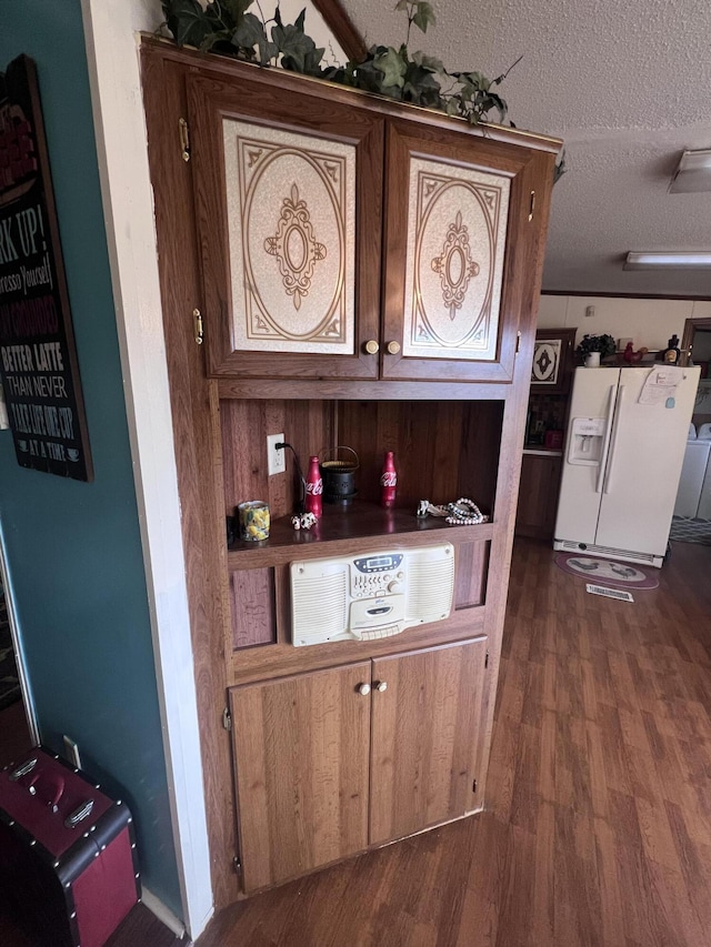 interior space featuring dark wood-type flooring, white refrigerator with ice dispenser, and a textured ceiling