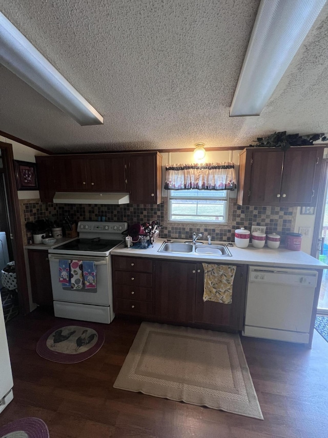 kitchen featuring under cabinet range hood, white appliances, a sink, light countertops, and dark wood-style floors