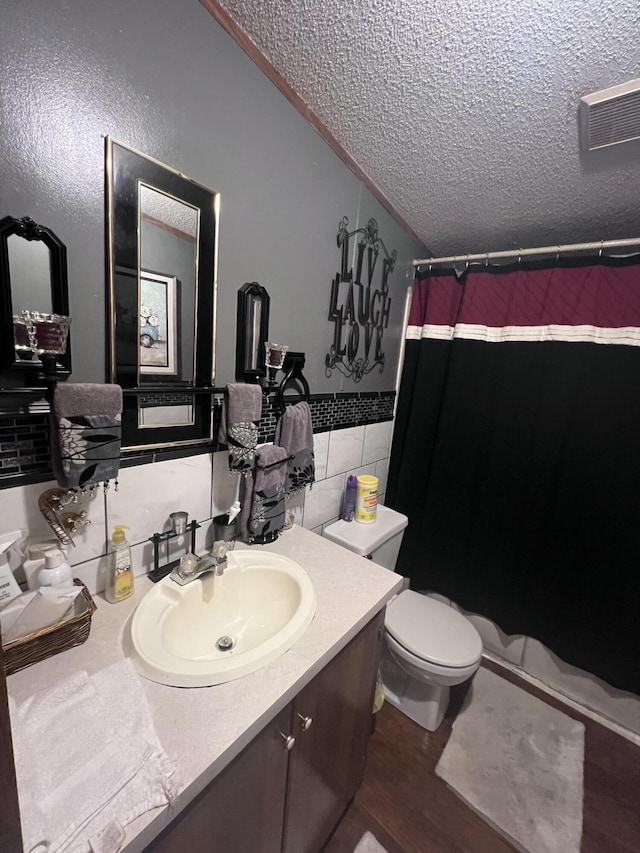 full bath with visible vents, toilet, a textured ceiling, vanity, and tile walls