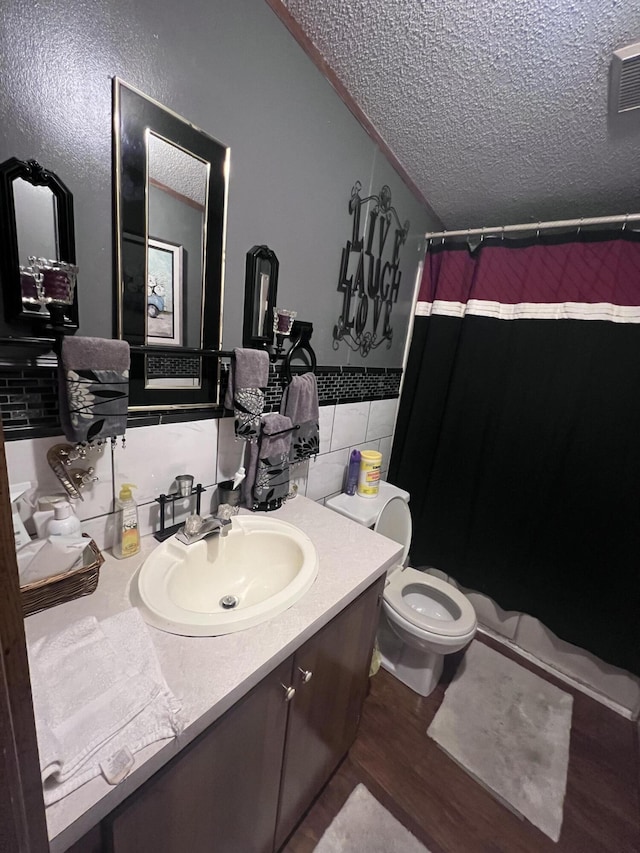 bathroom with tile walls, toilet, a textured ceiling, vanity, and wood finished floors