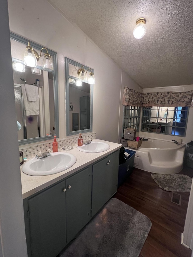 full bathroom with vaulted ceiling, visible vents, a sink, and wood finished floors