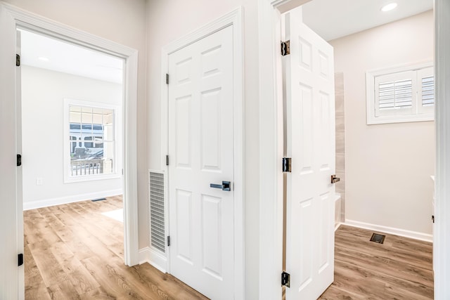 hall featuring light wood finished floors, baseboards, and recessed lighting