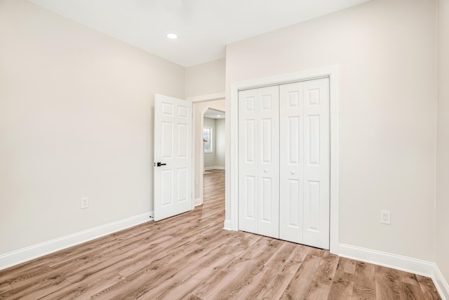 unfurnished bedroom featuring recessed lighting, a closet, light wood-style flooring, and baseboards