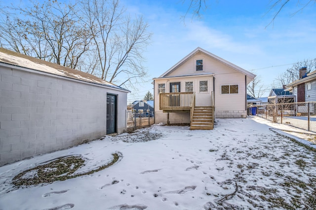 snow covered house featuring fence and a wooden deck