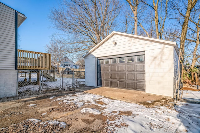 snow covered garage with a detached garage and fence