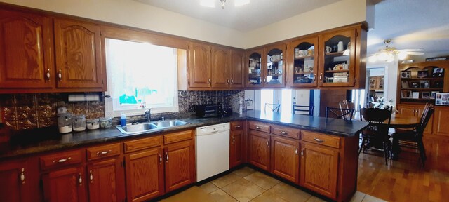 kitchen featuring brown cabinets, a sink, ceiling fan, dishwasher, and a peninsula