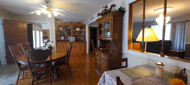 dining area with wood finished floors and ceiling fan with notable chandelier