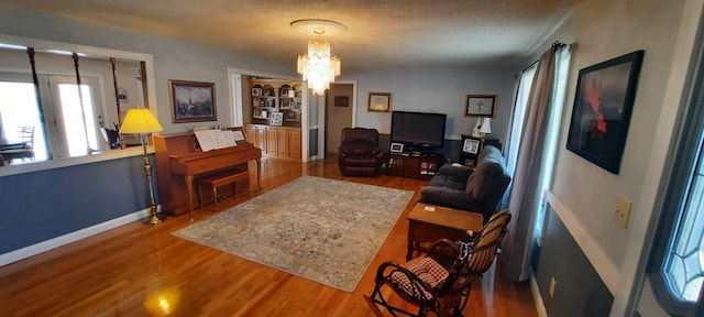 living area featuring baseboards, wood finished floors, and an inviting chandelier