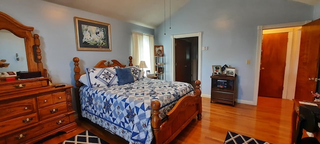 bedroom with vaulted ceiling, wood finished floors, and baseboards