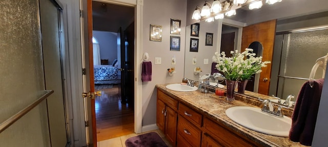 full bathroom featuring double vanity, an enclosed shower, a sink, and tile patterned floors