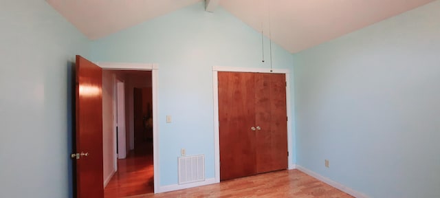 unfurnished bedroom with a closet, visible vents, light wood-style flooring, attic access, and baseboards