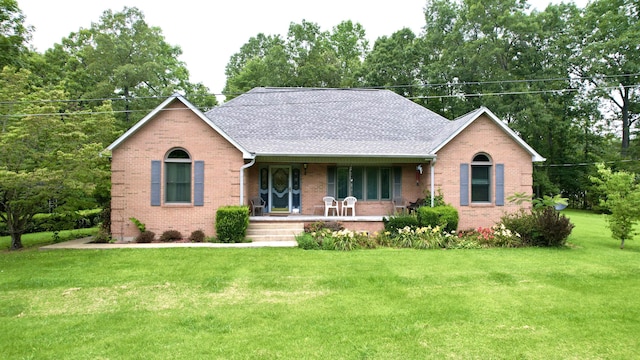 single story home featuring covered porch, a front lawn, and brick siding