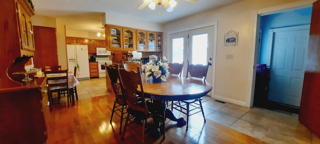 dining room with a ceiling fan, light wood-type flooring, visible vents, and baseboards