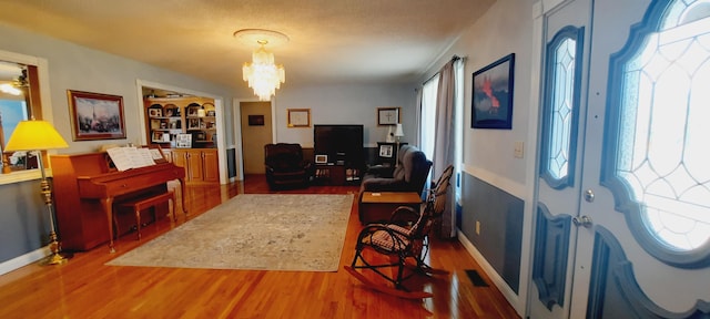 entryway with a chandelier, wood finished floors, and baseboards