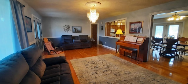 living area featuring baseboards, wood finished floors, and a notable chandelier