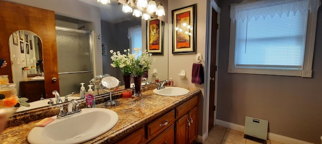 full bathroom with double vanity, a stall shower, tile patterned flooring, and a sink