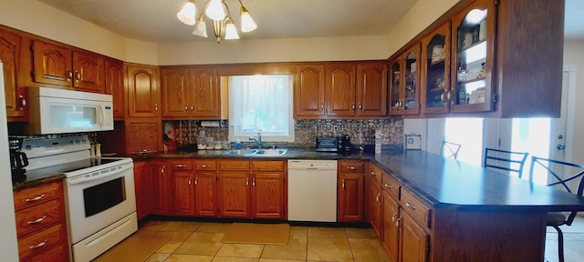 kitchen featuring white appliances, decorative backsplash, glass insert cabinets, a peninsula, and a sink