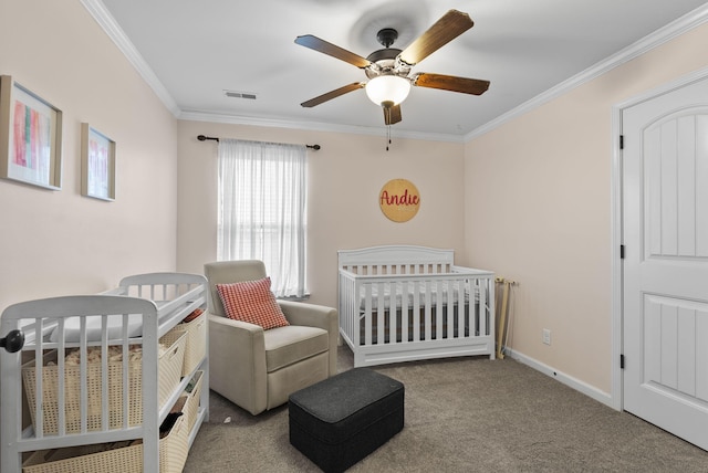 carpeted bedroom with a ceiling fan, baseboards, visible vents, a nursery area, and crown molding