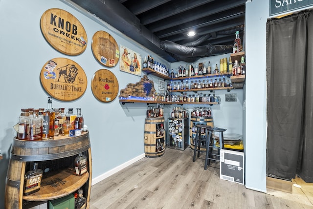 bar with a bar, wood finished floors, and baseboards