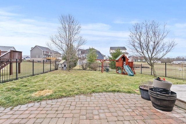 view of yard featuring a patio, a playground, a fenced backyard, and a residential view