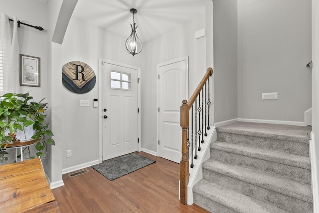 foyer featuring stairs, visible vents, baseboards, and wood finished floors