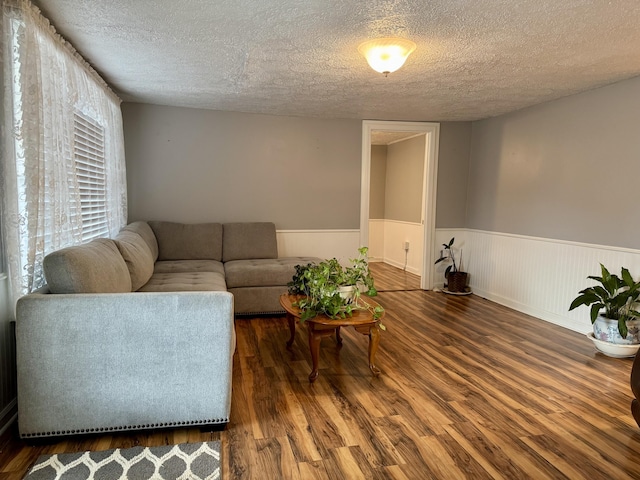 living area with wainscoting, a textured ceiling, and wood finished floors