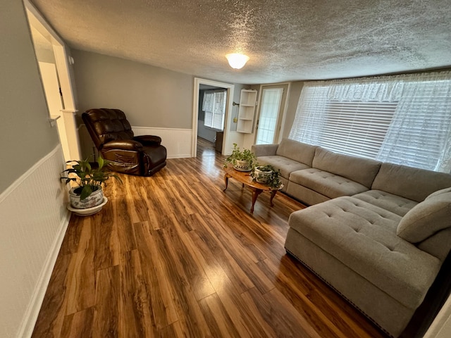 living room featuring wainscoting, a textured ceiling, and wood finished floors