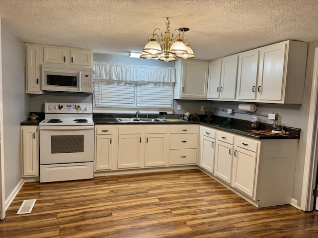 kitchen with wood finished floors, white appliances, and a sink