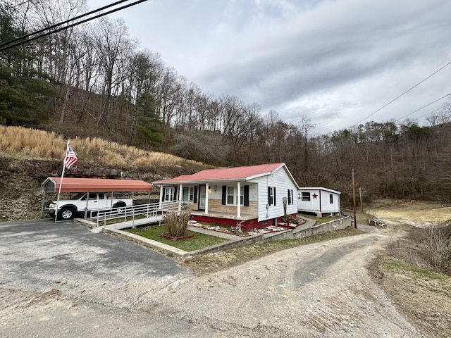 view of front of house with covered porch, driveway, and metal roof