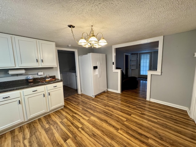 kitchen with dark wood-style floors, dark countertops, white refrigerator with ice dispenser, and washing machine and clothes dryer