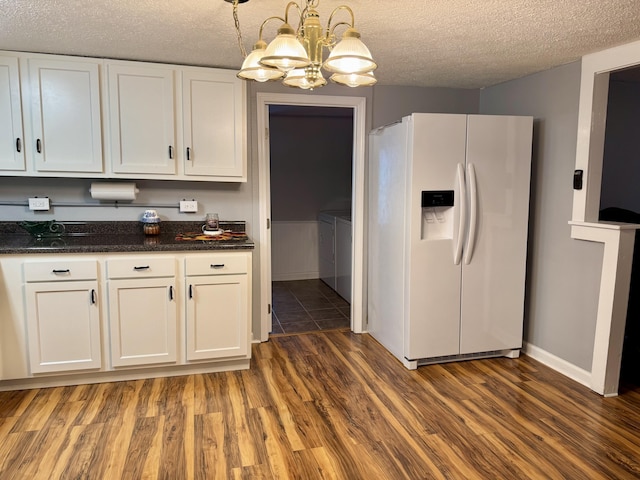 kitchen featuring white cabinets, wood finished floors, independent washer and dryer, a textured ceiling, and white fridge with ice dispenser