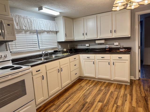 kitchen with dark wood-style floors, white cabinetry, a sink, a textured ceiling, and white appliances